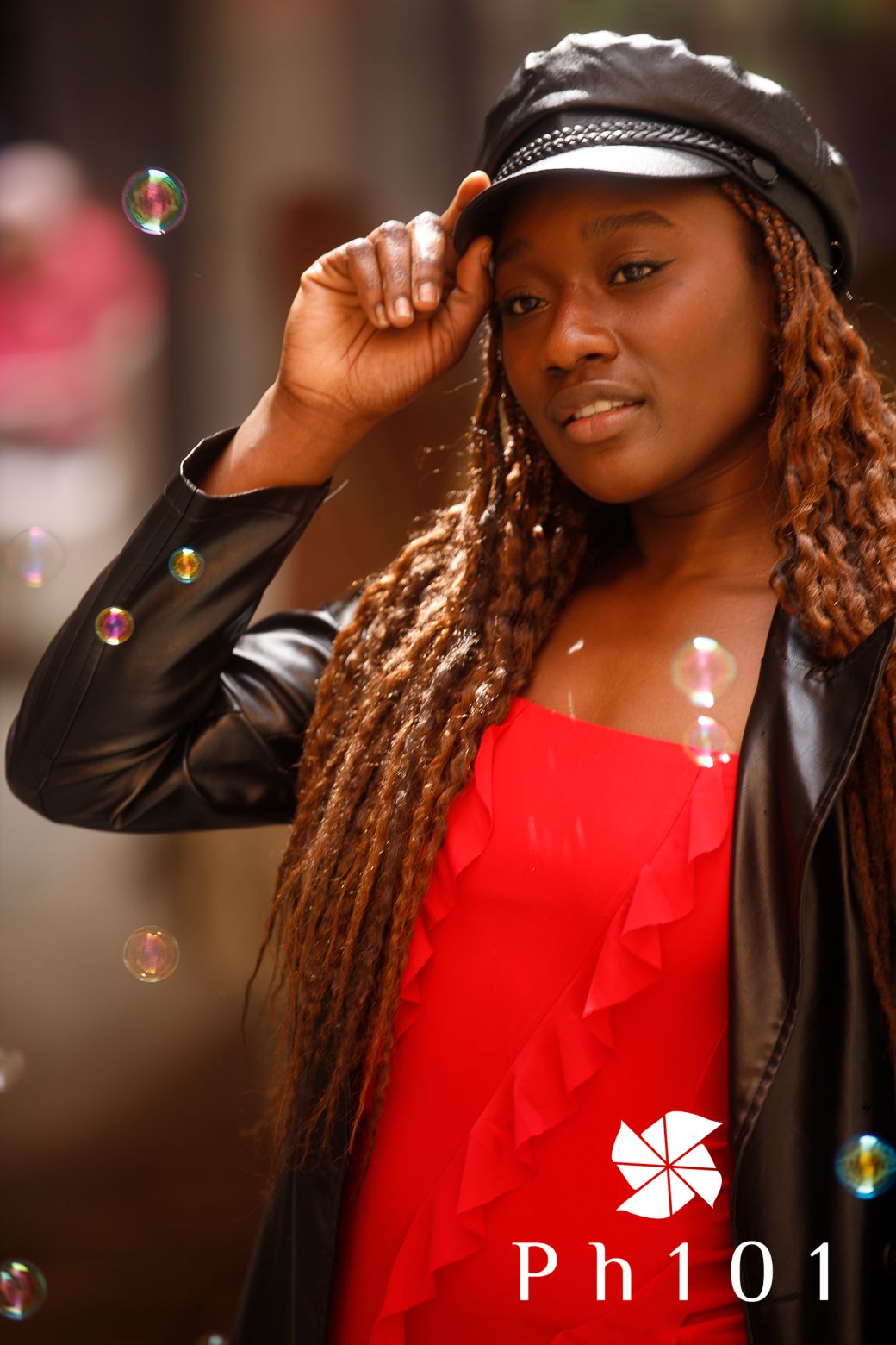 Stylish portrait with leather jacket, red top and cap with soap bubbles floating in foreground.