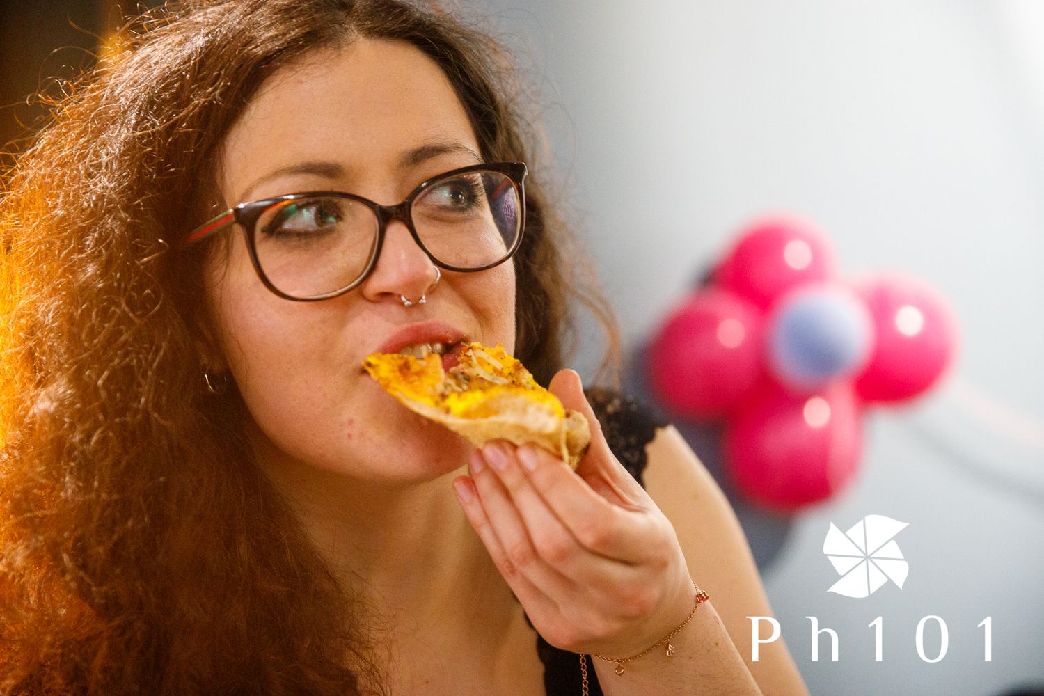 Someone taking a bite of pizza in a warmly lit restaurant setting.