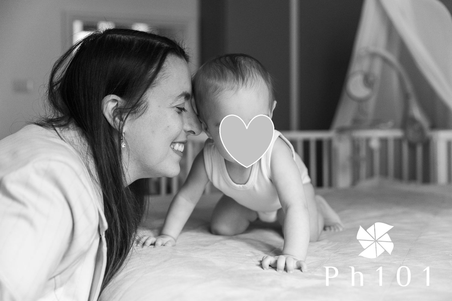 Black and white image showing a parent and baby sharing a joyful moment together on a bed.