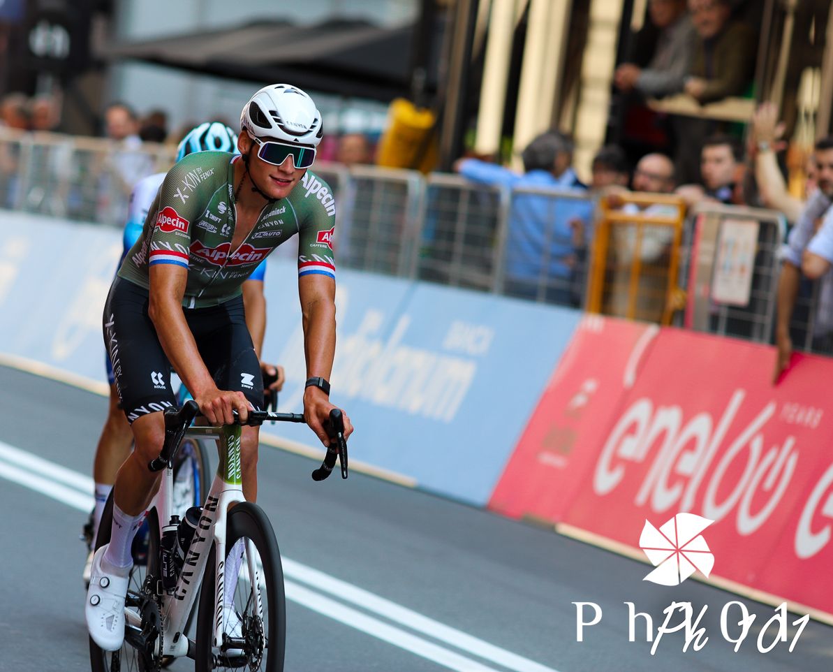 Professional cyclist racing during a competitive event with crowd barriers visible.