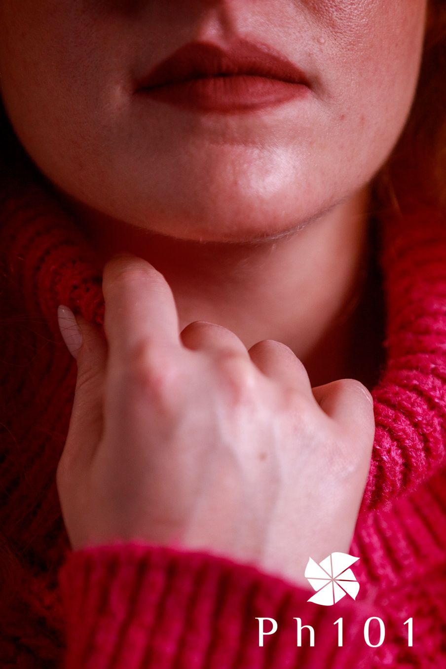 Artistic close-up of hands and lips wearing bright pink knit sweater.