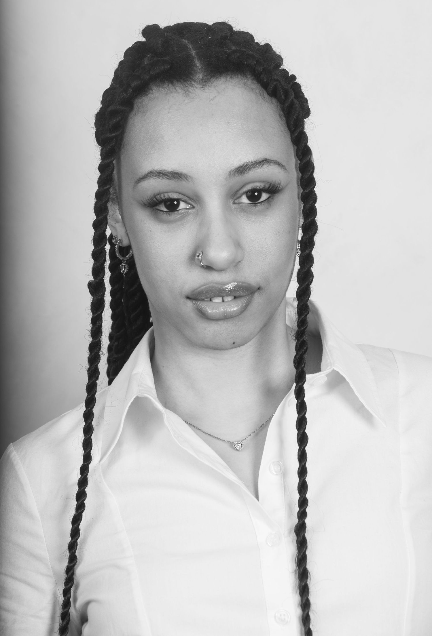 Professional headshot featuring long braided hairstyle and white button-down shirt.