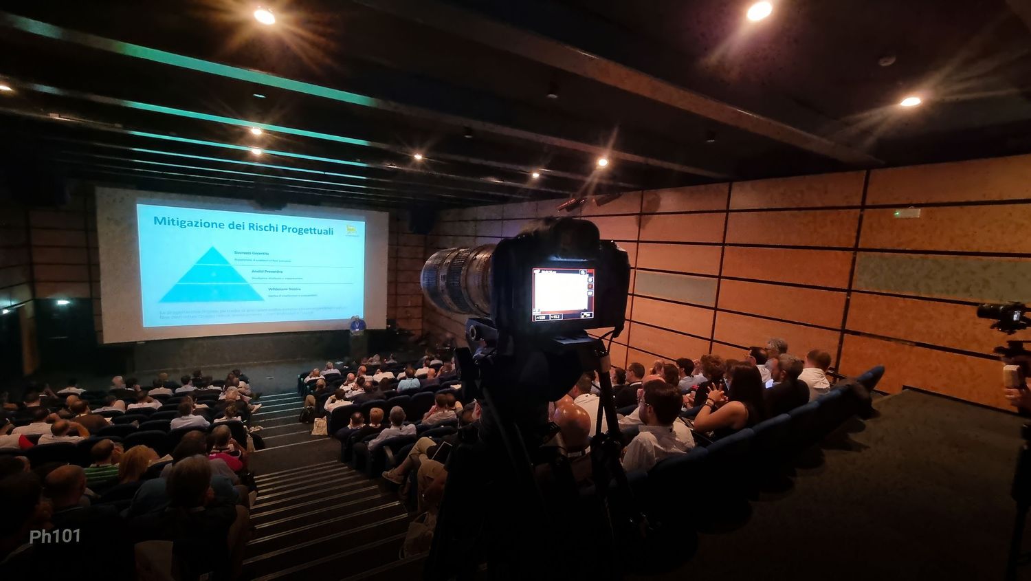 Panoramic view of a dimly lit auditorium during a presentation with projection screen.