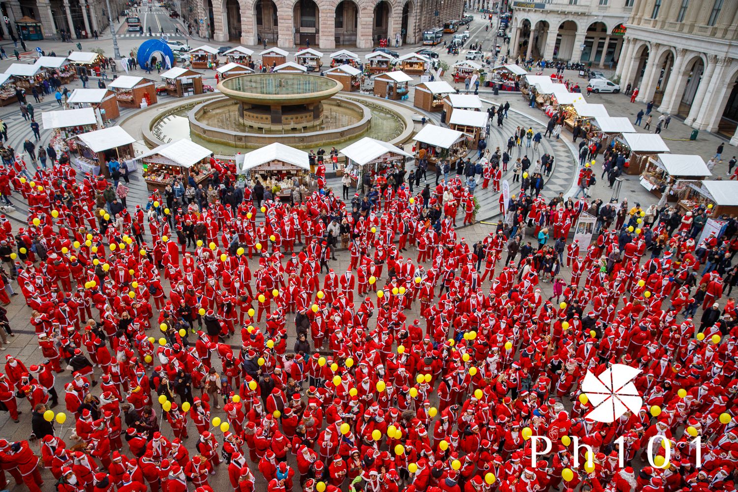Aerial view of large crowd wearing red gathered in historic European plaza.