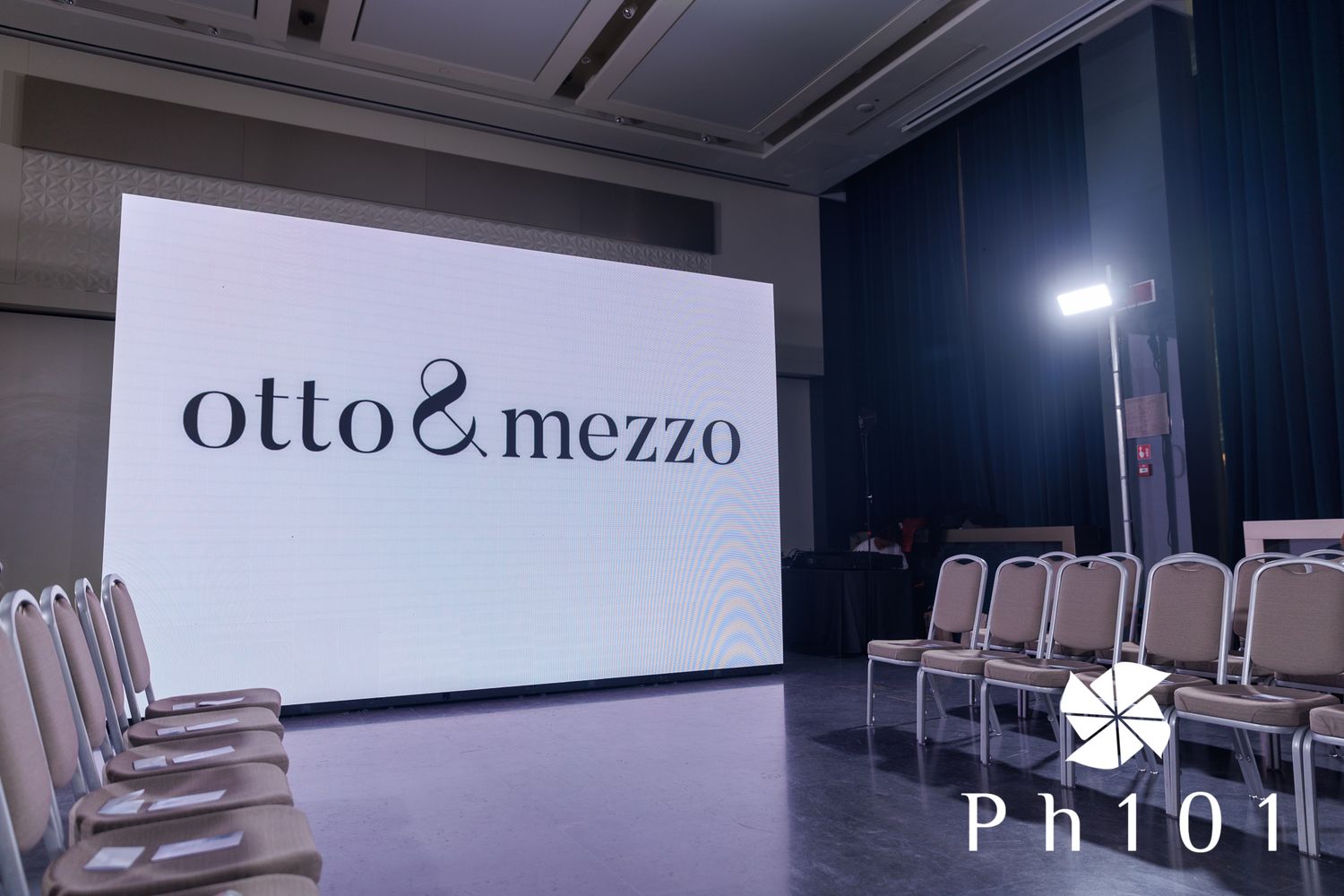 Empty modern conference room with chairs and 'otto&mezzo' signage on wall.