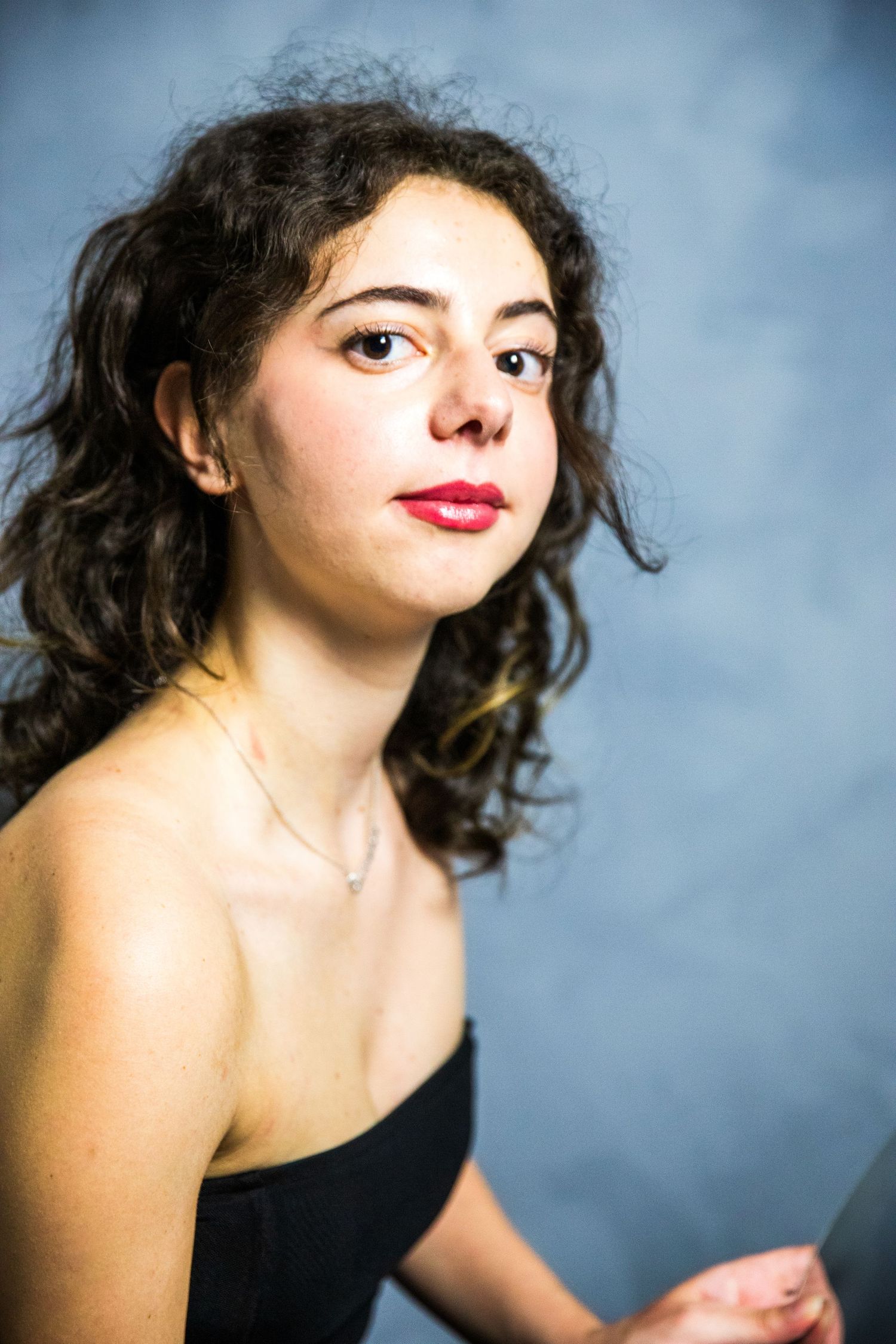 Portrait series showing expressive poses and red lipstick against blue studio backdrop.