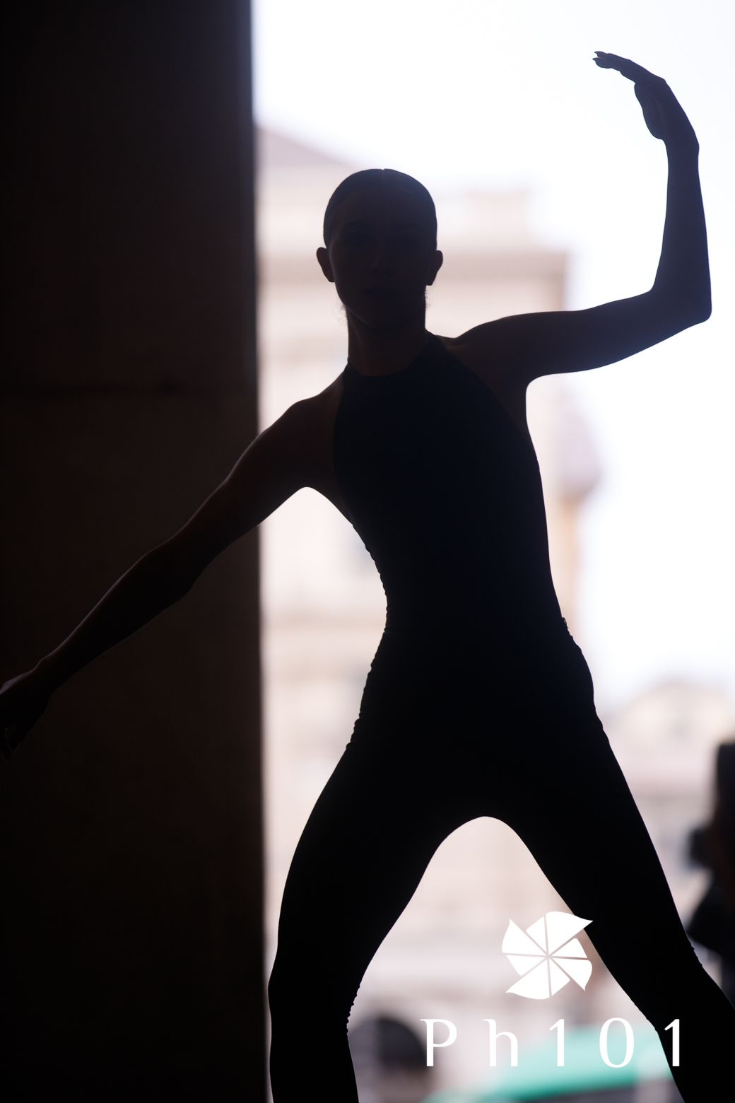 Artistic silhouette of dancer striking dramatic pose against bright background.