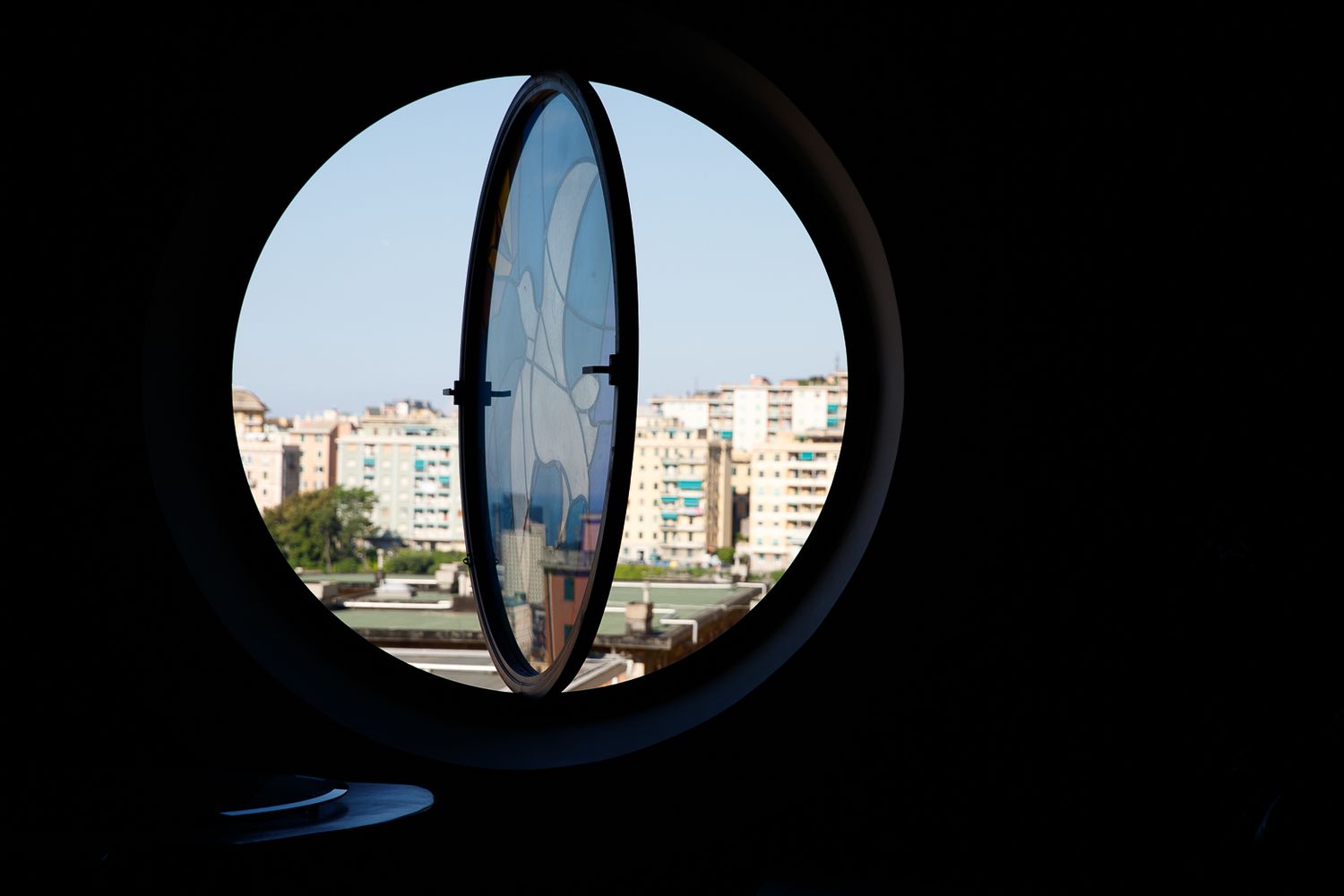 Circular window views of city buildings against dark background.