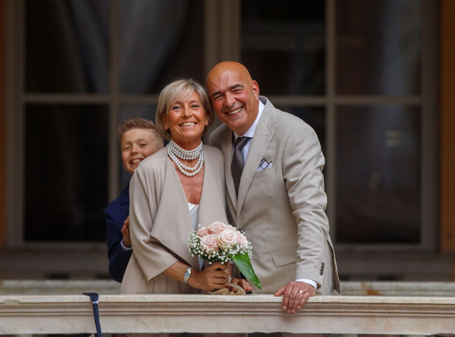 Couple posing together by a window with flowers and smiles.