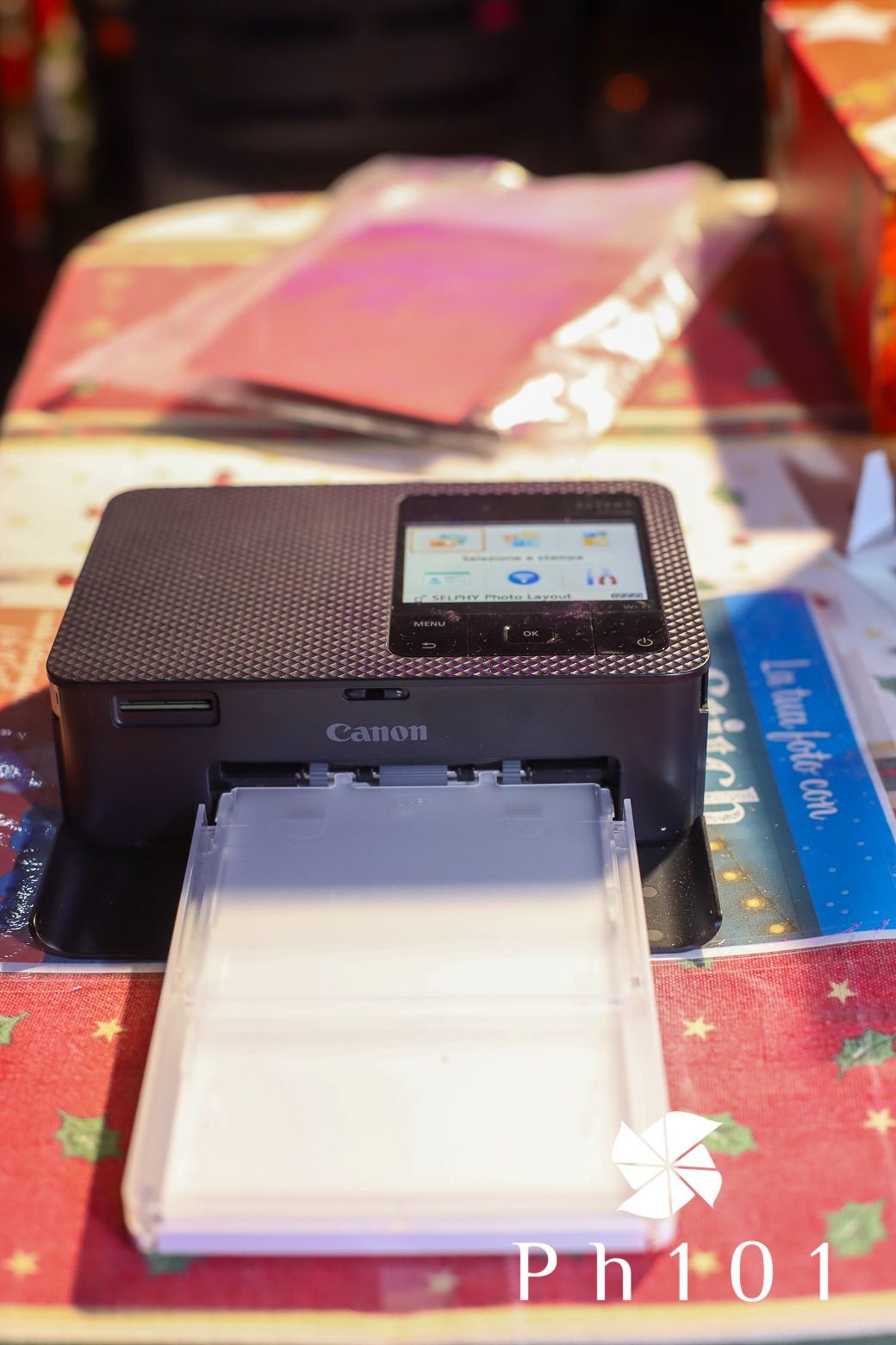 Close-up of a Canon printer device on a red patterned tablecloth.