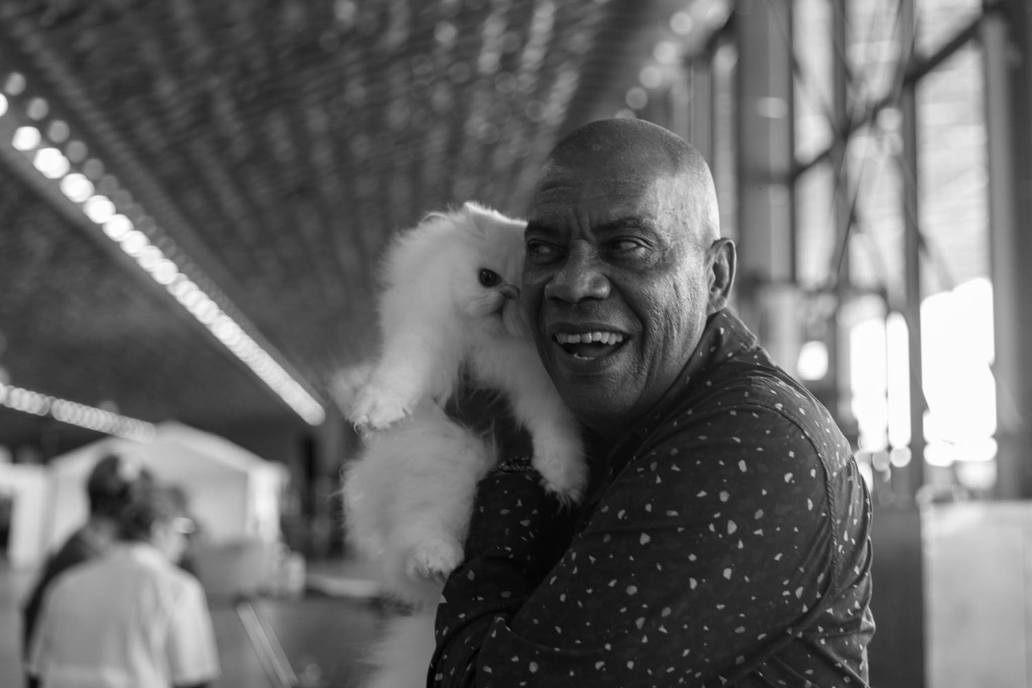Black and white candid photo of person laughing with sparkly polka dot shirt.
