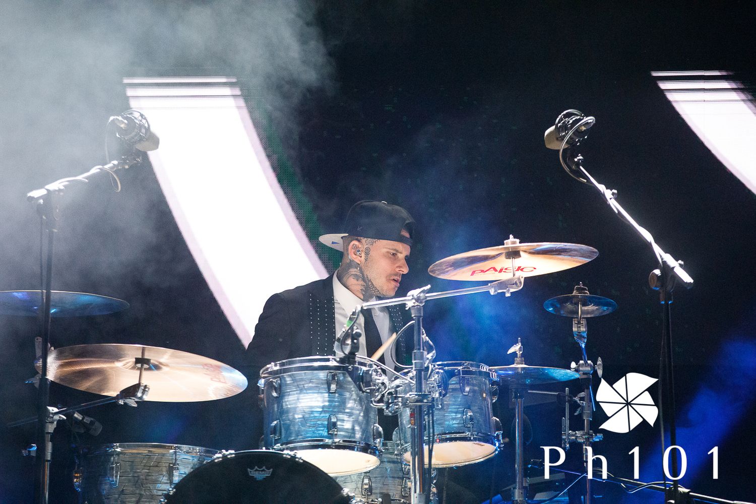 Drummer performing on stage with dramatic lighting and smoke effects.