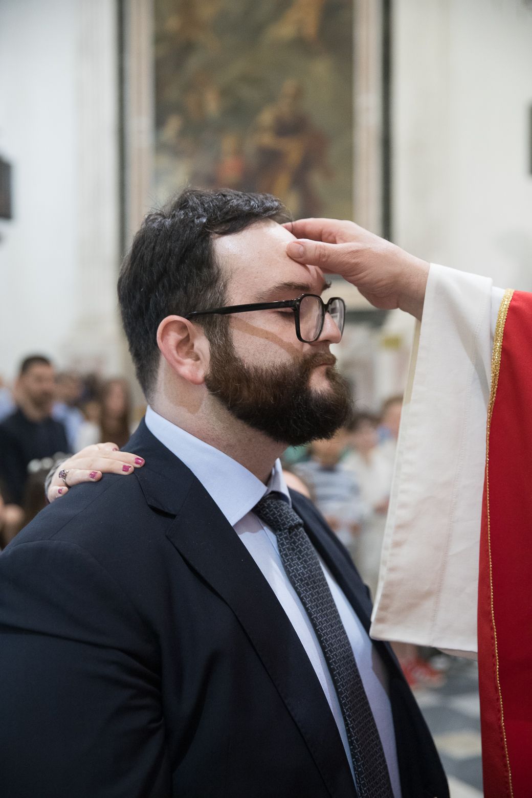 A priest administers a blessing during a religious ceremony in a church.