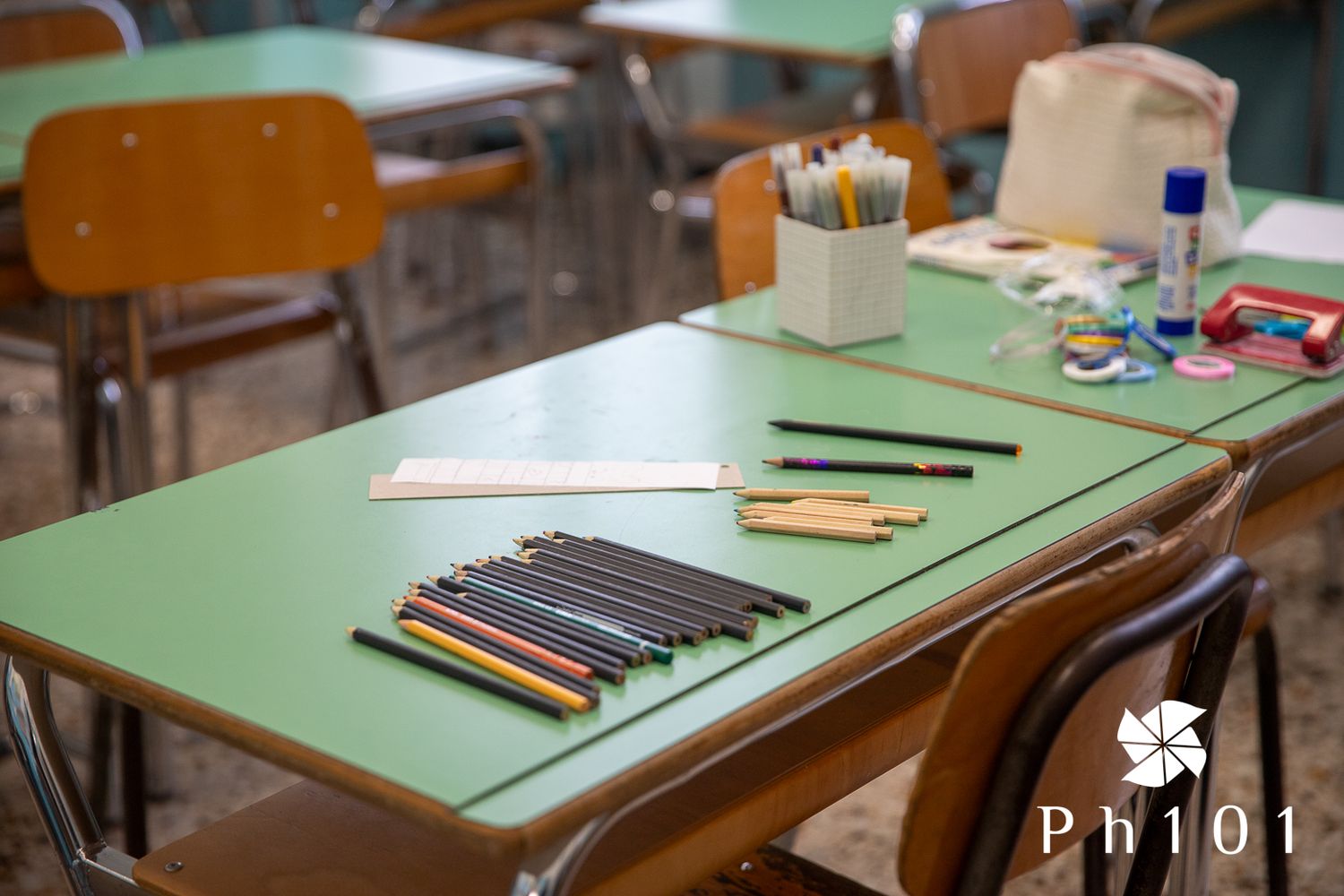 Green classroom desk with art supplies and materials arranged neatly on top.