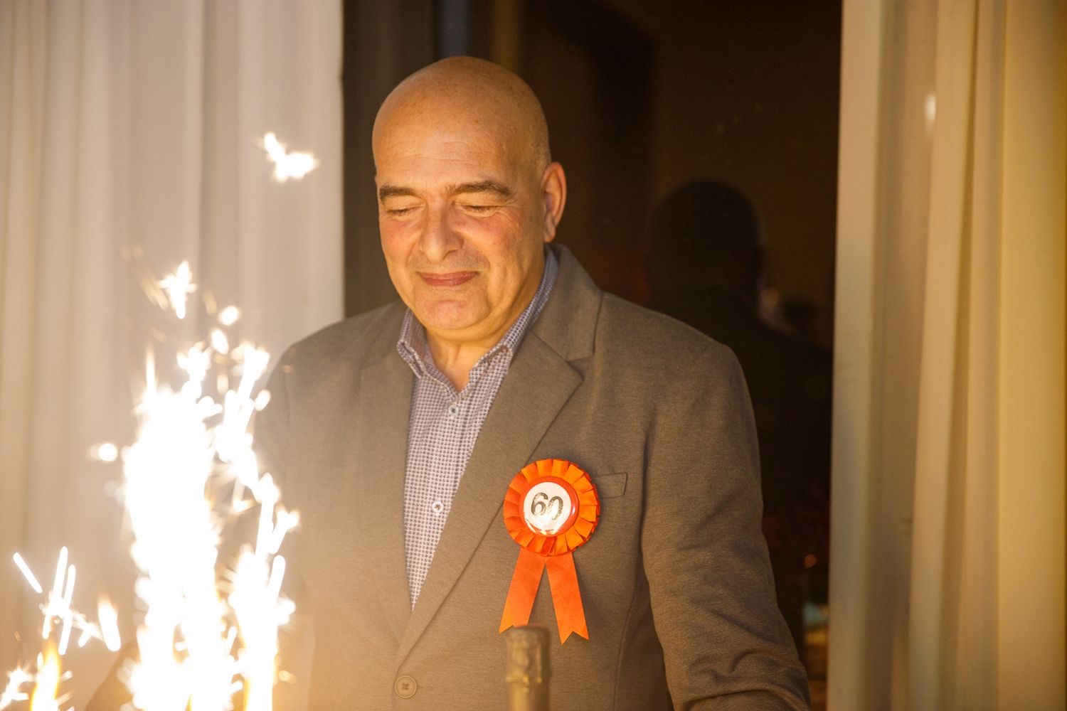 People smiling and celebrating at an elegant indoor event with sparklers in the background.