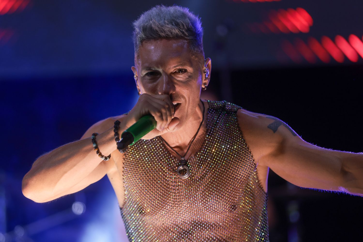 Performer in sparkly costume under dramatic stage lighting.