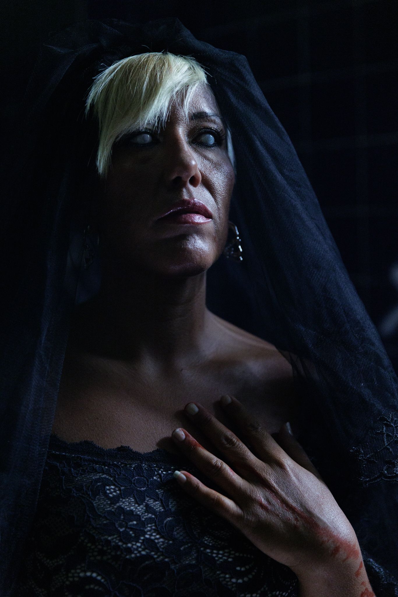 Dramatic portrait in dark lighting with black lace veil.