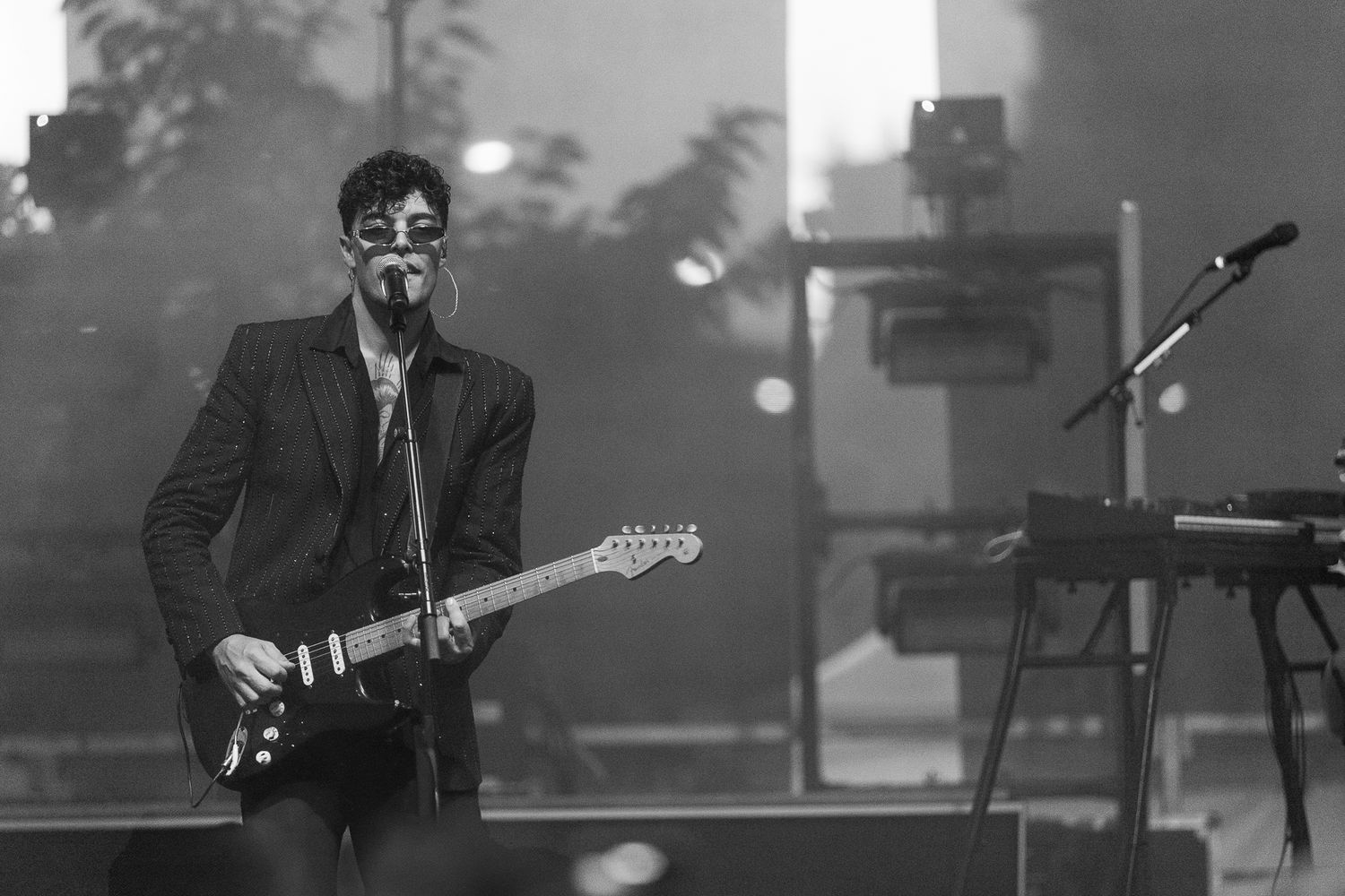 Musicians perform on stage in black and white with dramatic lighting effects.