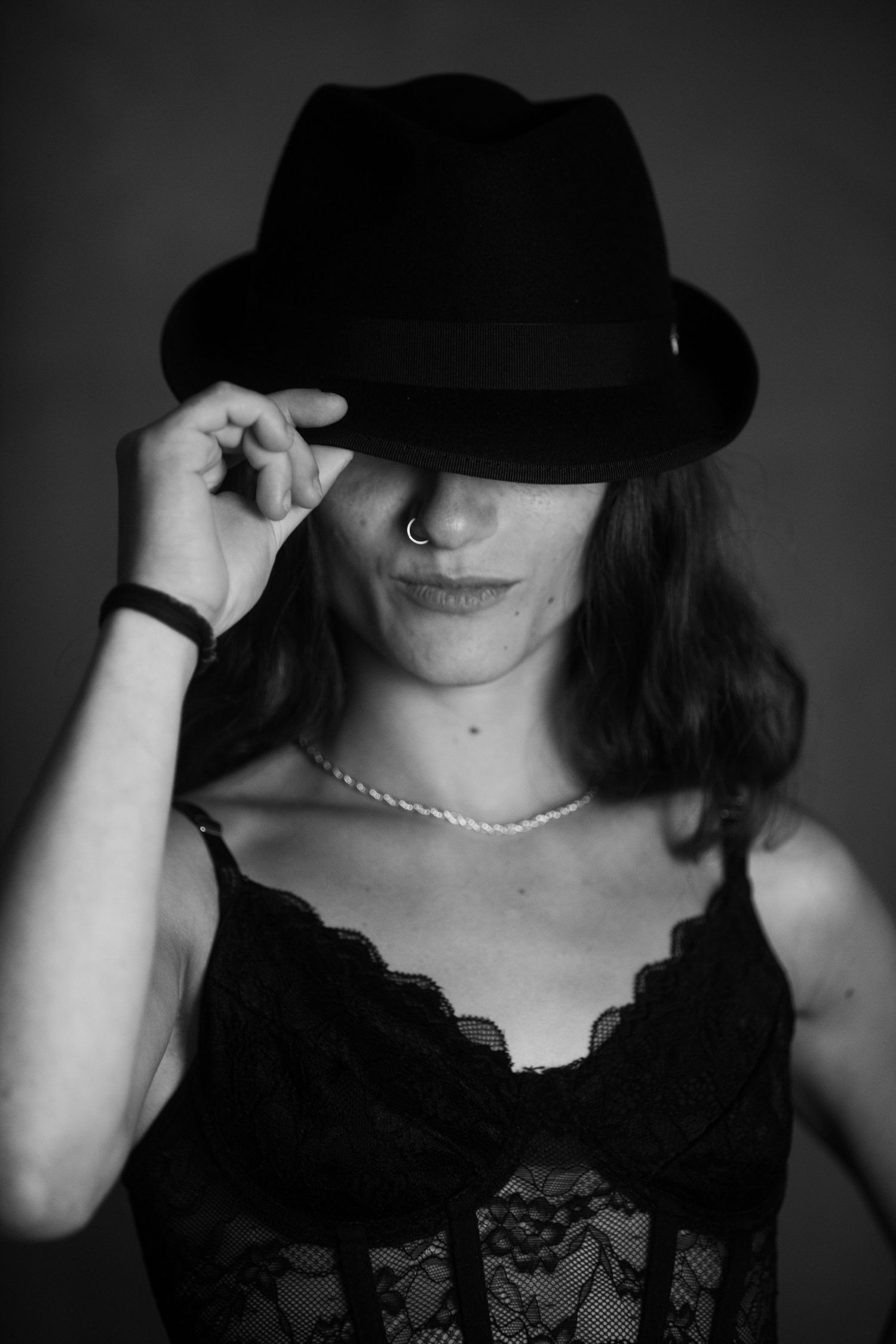 Dramatic black and white portraits featuring a black lace top and fedora hat.
