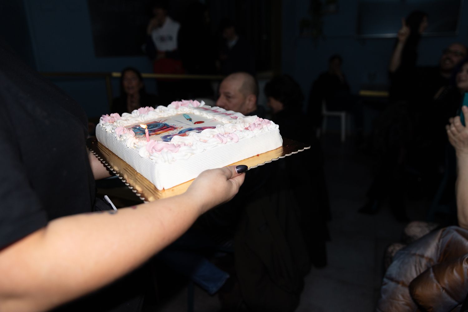 A slice of frosted sheet cake with colorful sprinkles being served on a white paper plate.