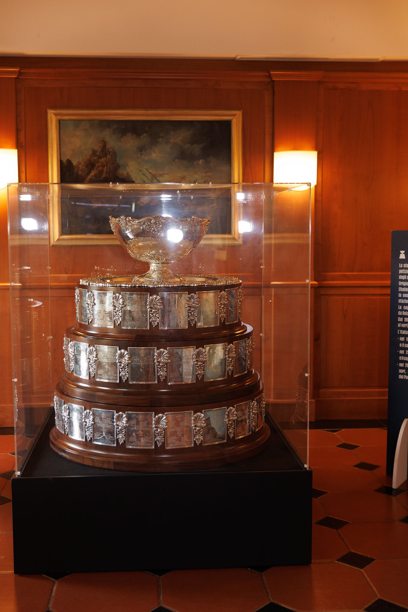 Trophy display case with silver championship cup in wood-paneled room.