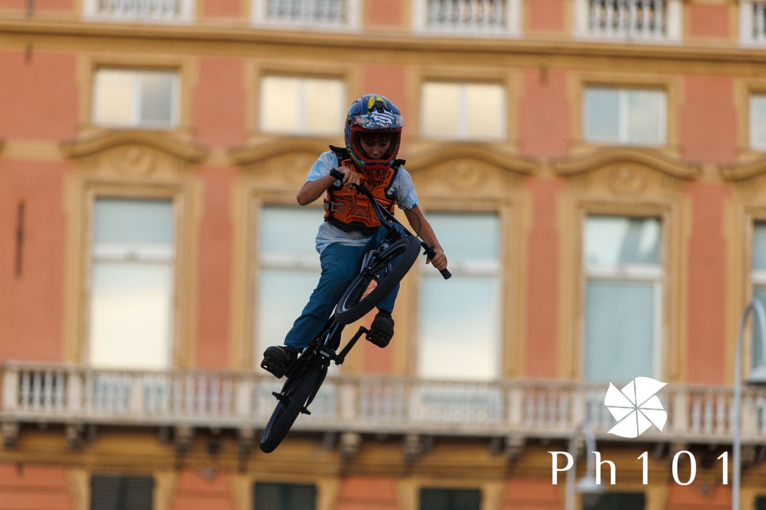 BMX rider performing aerial stunt against historic building facade.