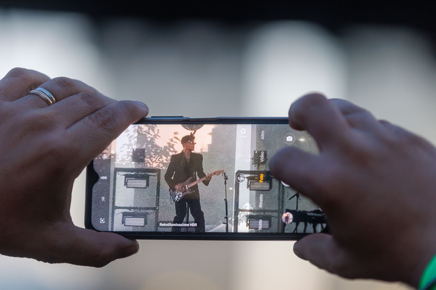 Hands holding a smartphone to capture video footage of a performance.