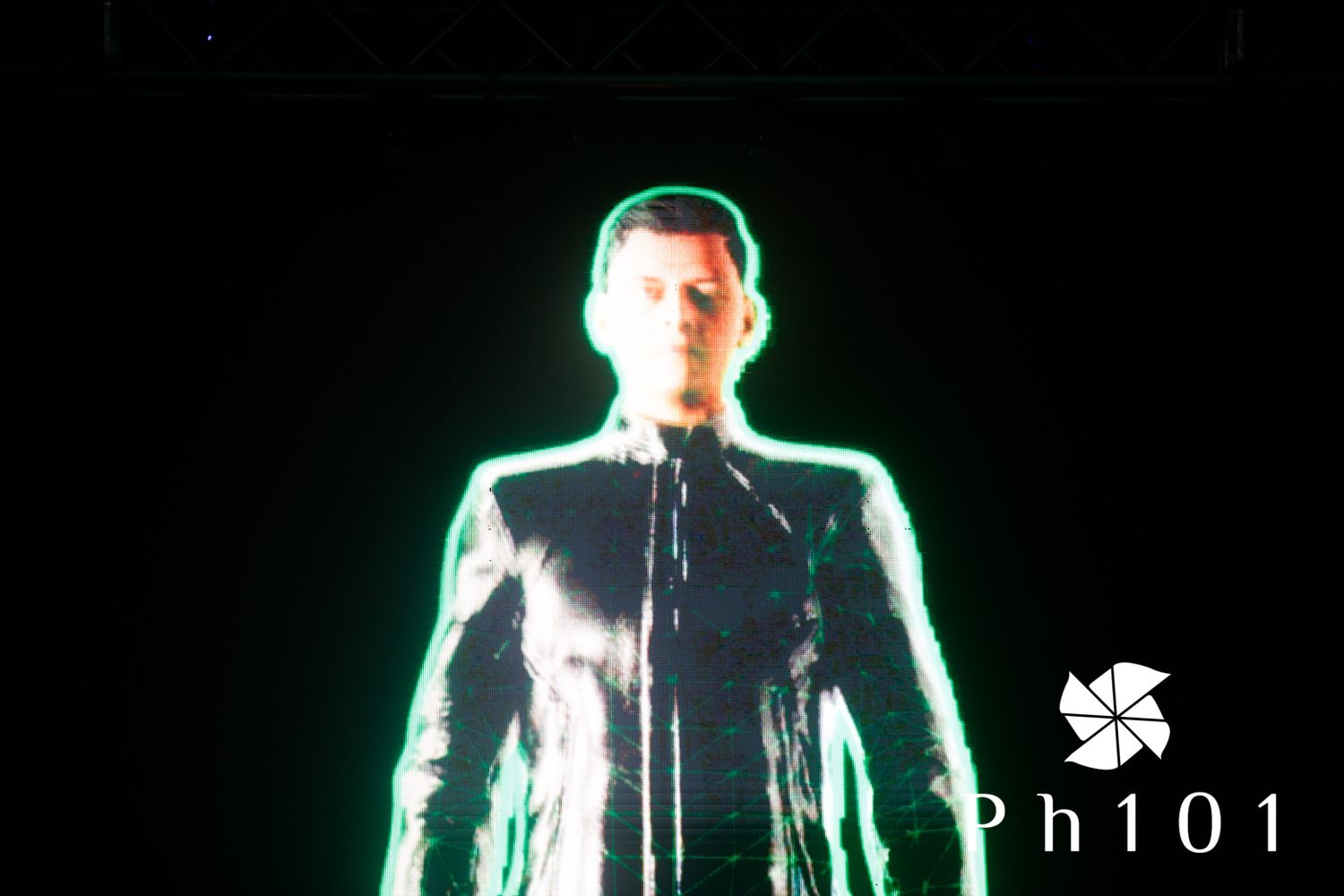 Silhouetted figure illuminated by green lighting on dark stage during performance.