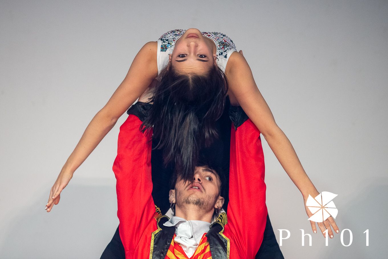 Two performers creating a dramatic acrobatic pose with one balanced upside down.