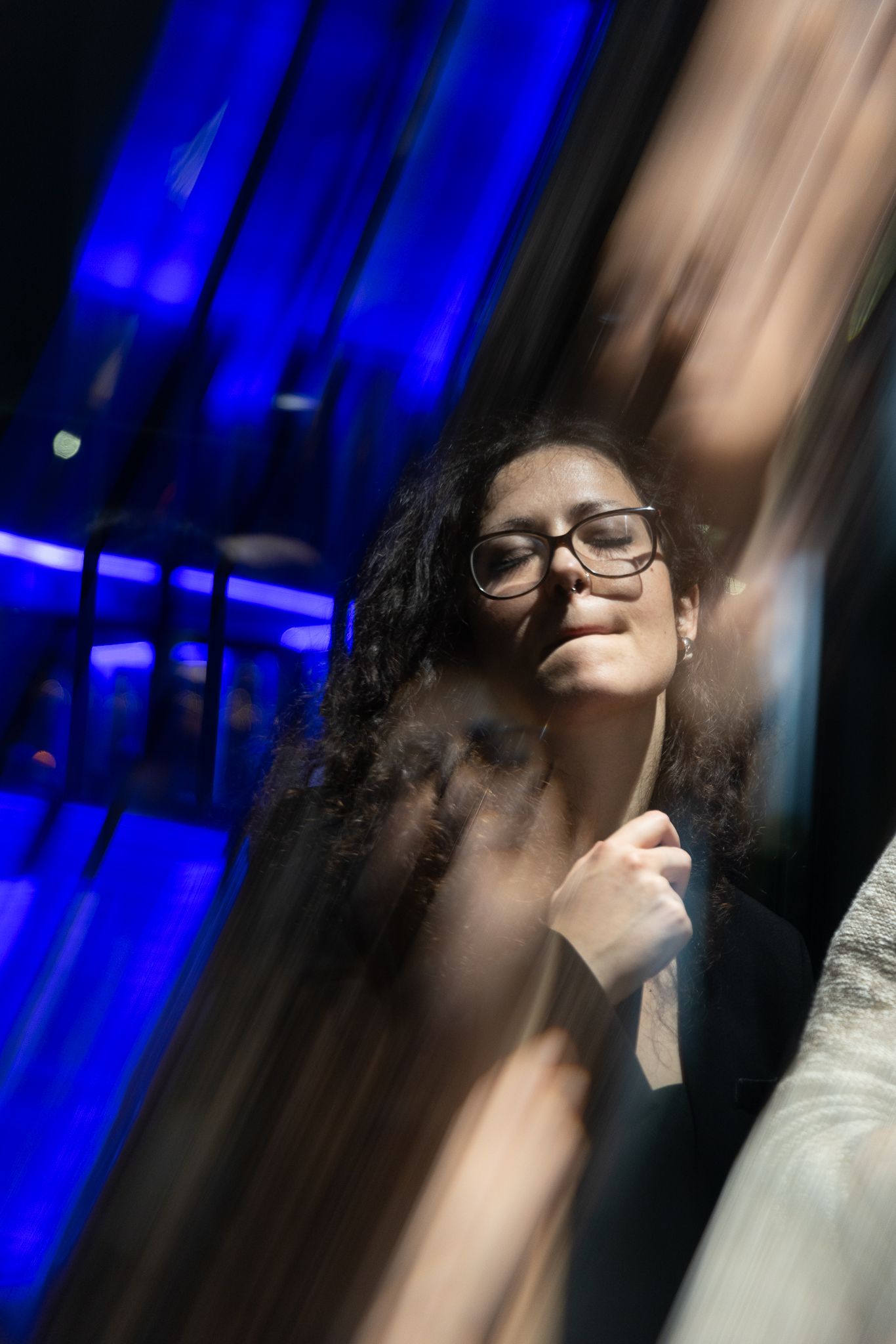 Artistic portrait series with blue lighting and motion blur effects showing a person wearing glasses against a dark background.
