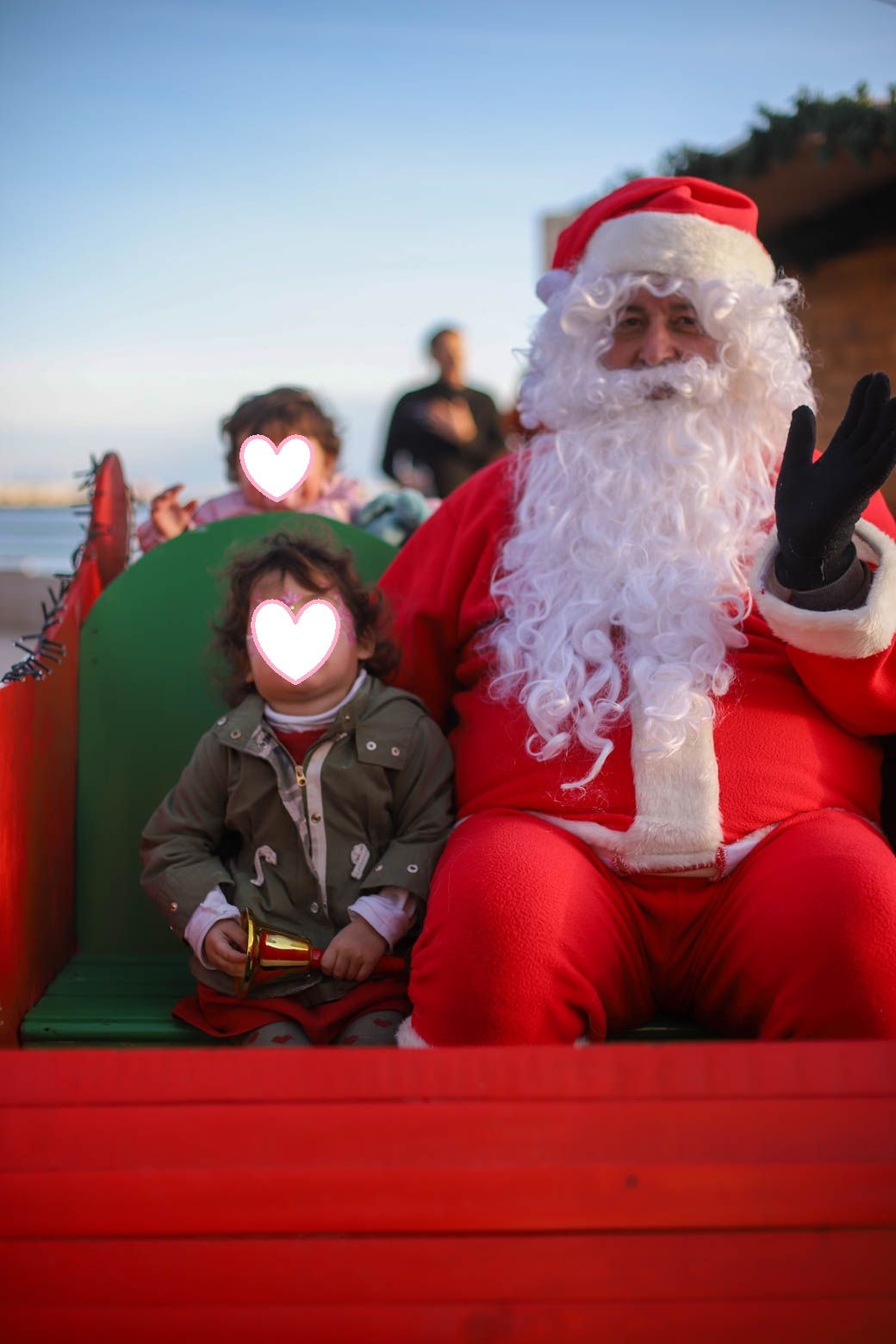 Holiday performers sitting together on a decorated red and green sleigh outdoors.