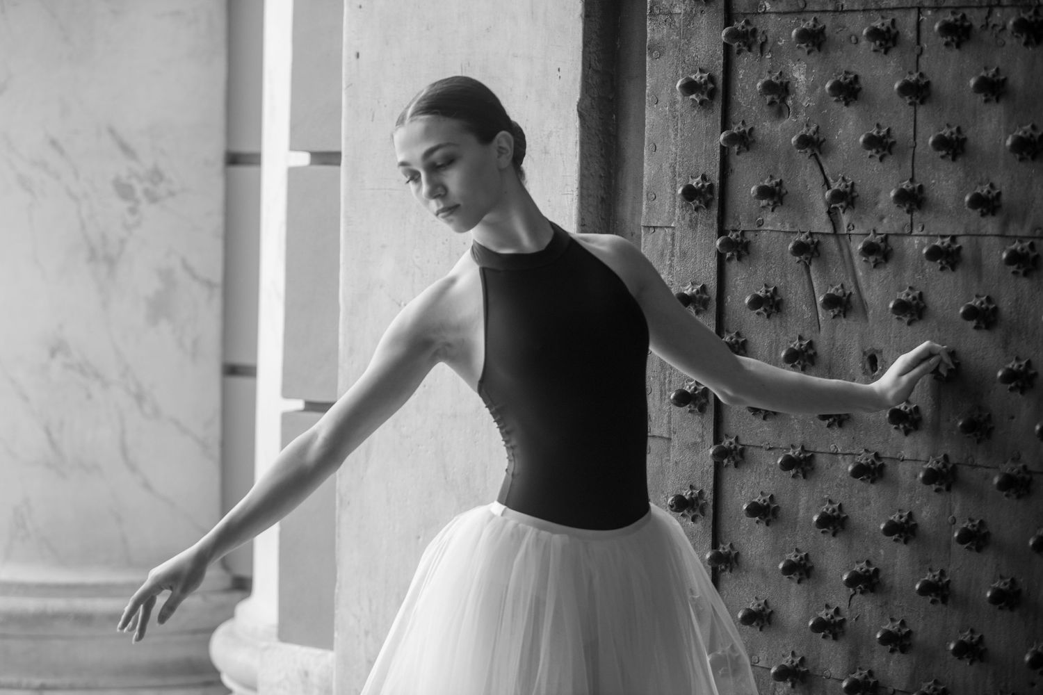 Dance performance sequence in black and white showing graceful movements against marble wall.