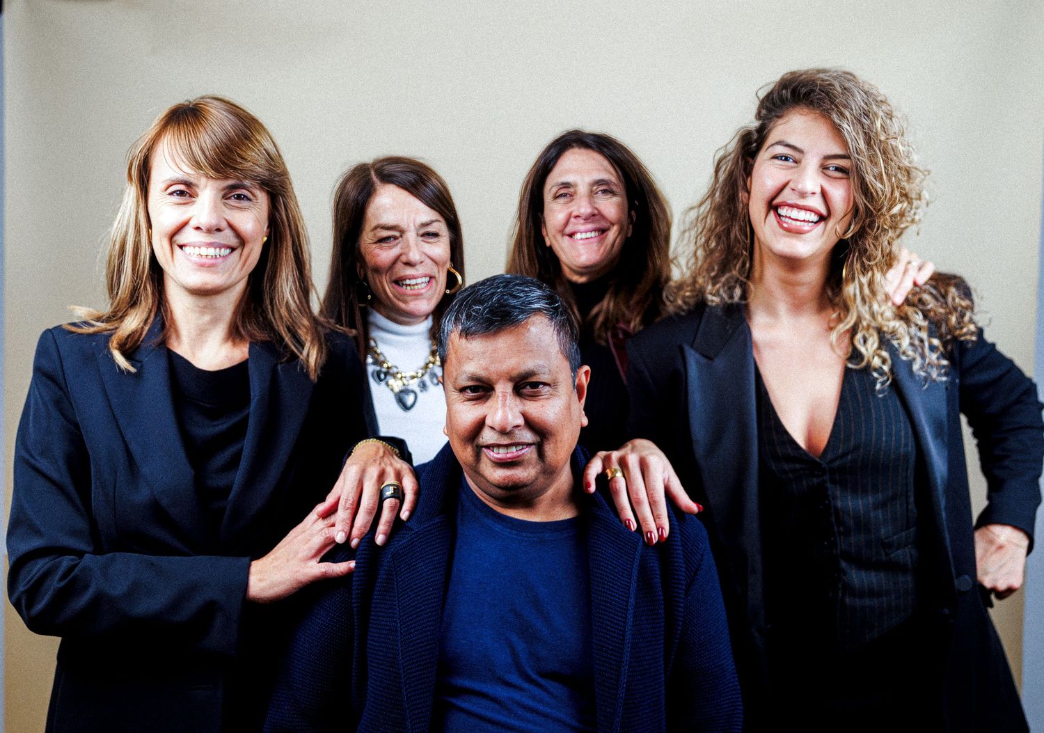 Group portrait of people wearing matching black outfits against white background.