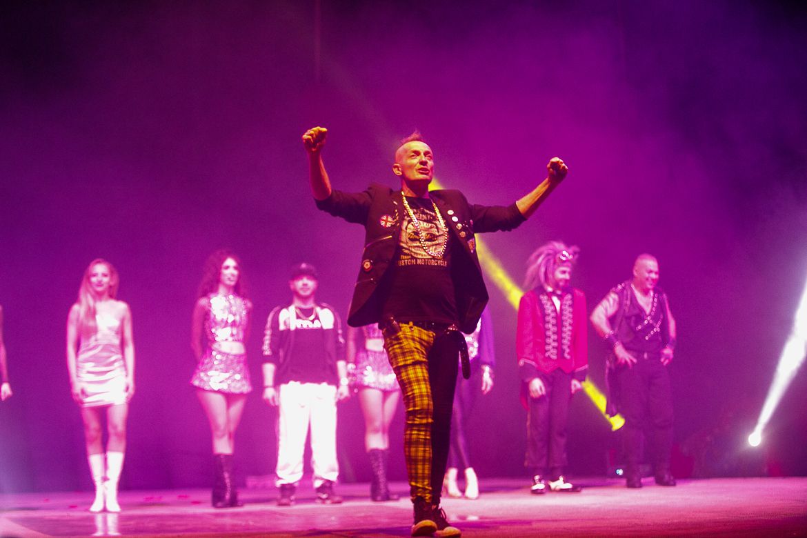Group performance on stage with purple lighting and dramatic effects.