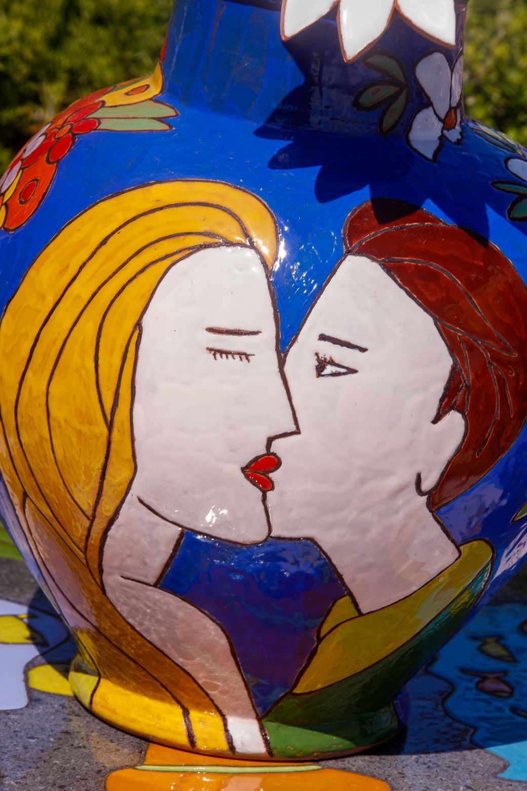 Colorful ceramic art piece depicting kissing faces in blue and yellow.