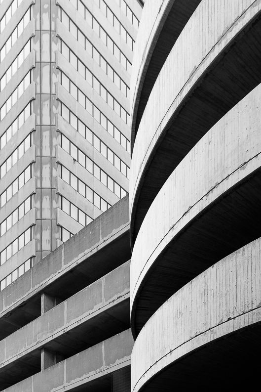 Modern parking structure with curved concrete levels creating rhythmic architectural patterns in black and white.