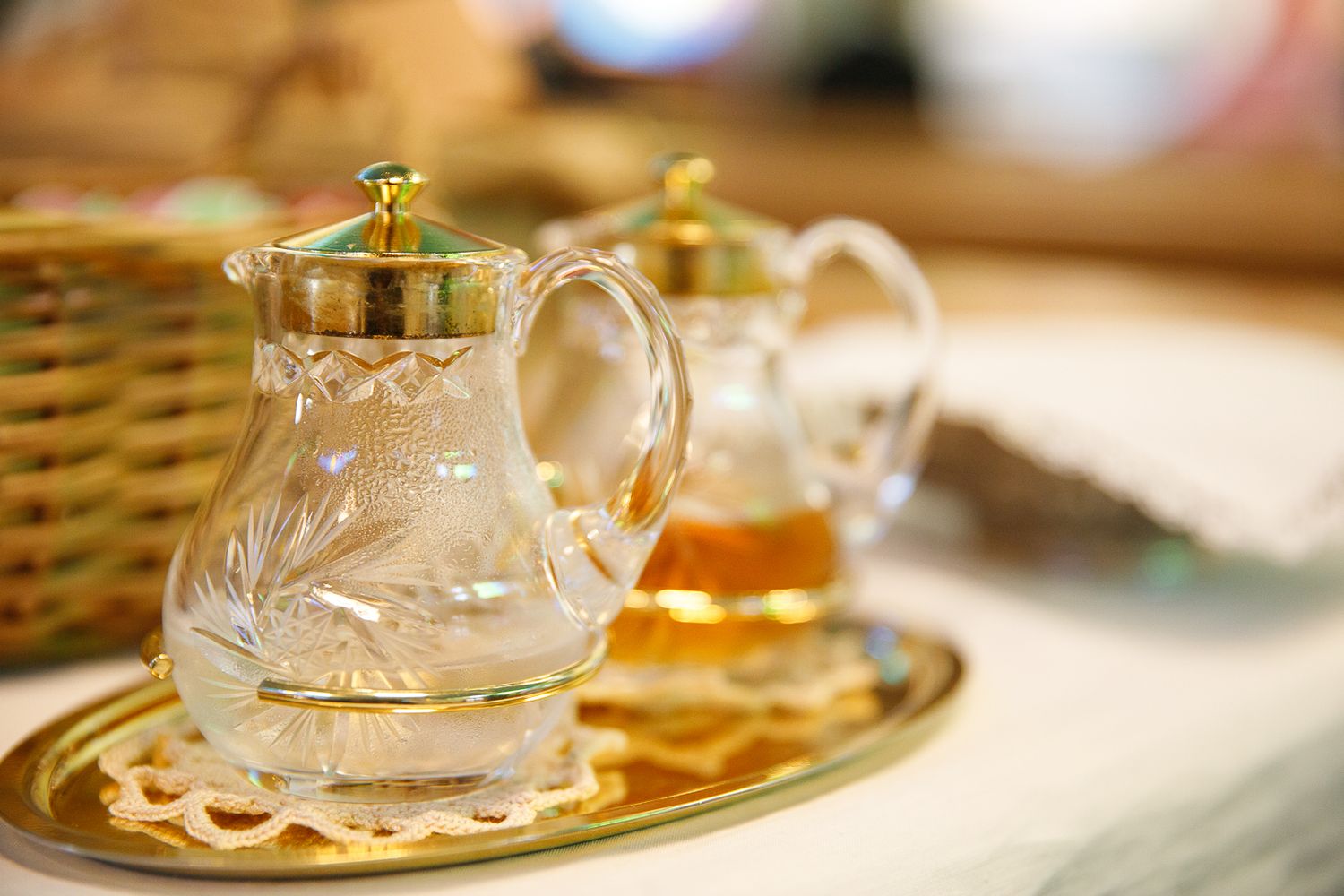 Glass teapots and serving dishes arranged on golden tray.