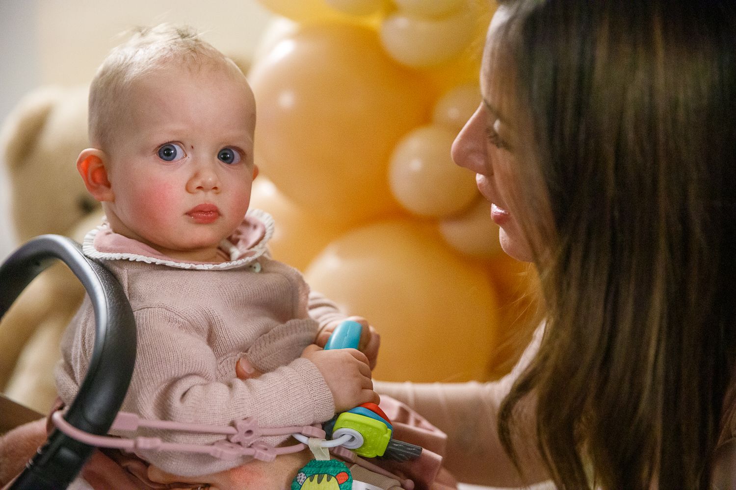 Baby interacting with parent against warm golden background.