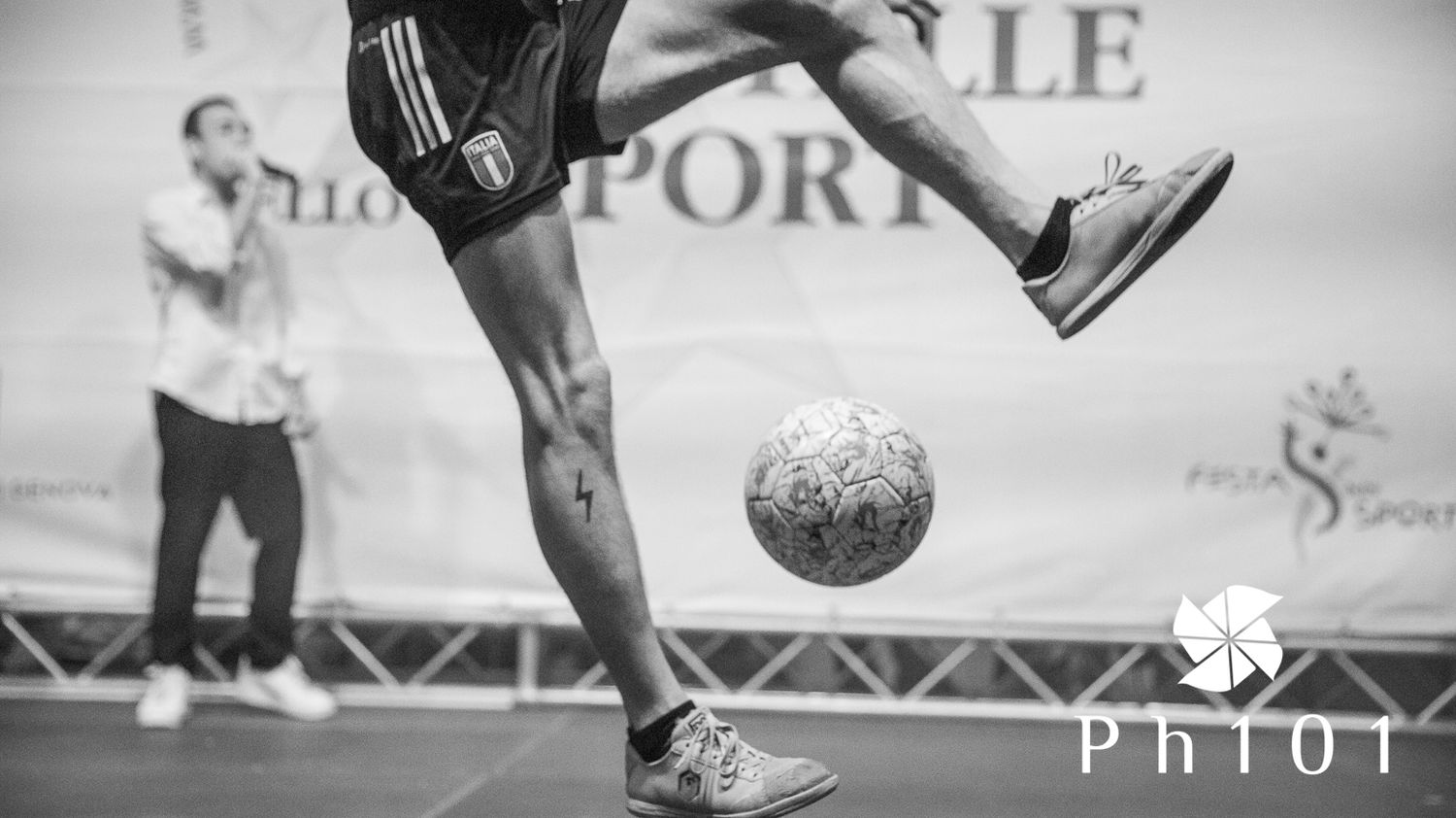 Black and white shot of a soccer player's foot controlling a ball during a sporting event.