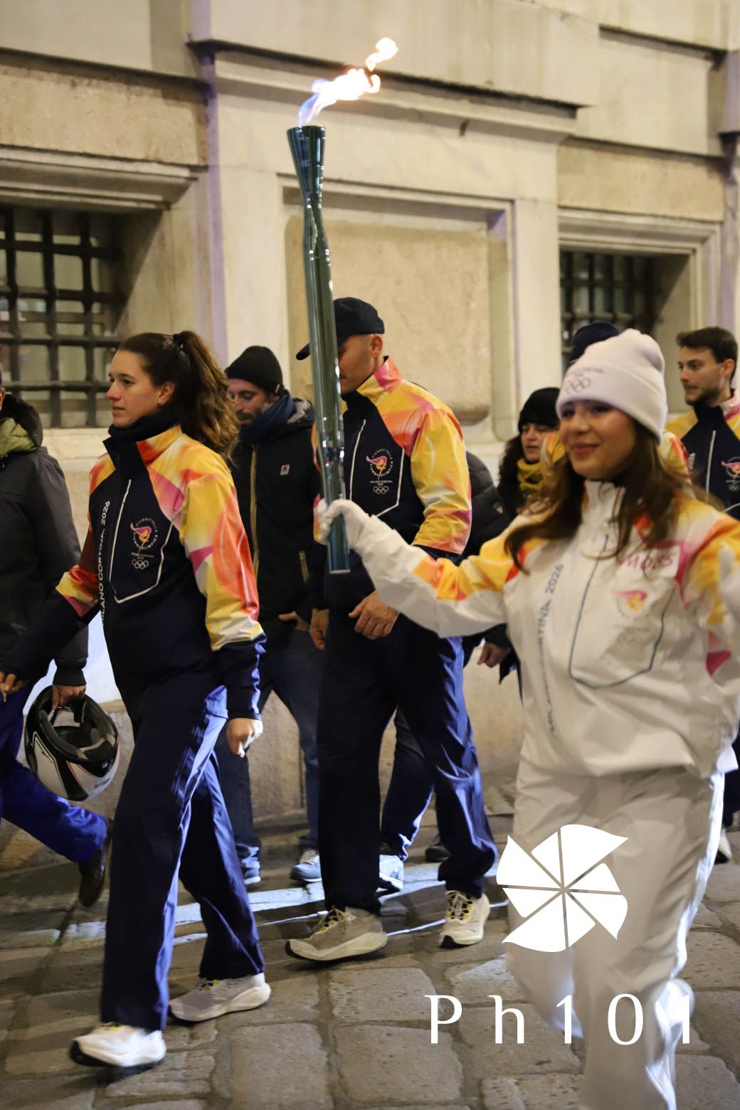 Group of people in colorful sportswear lined up against a building wall.