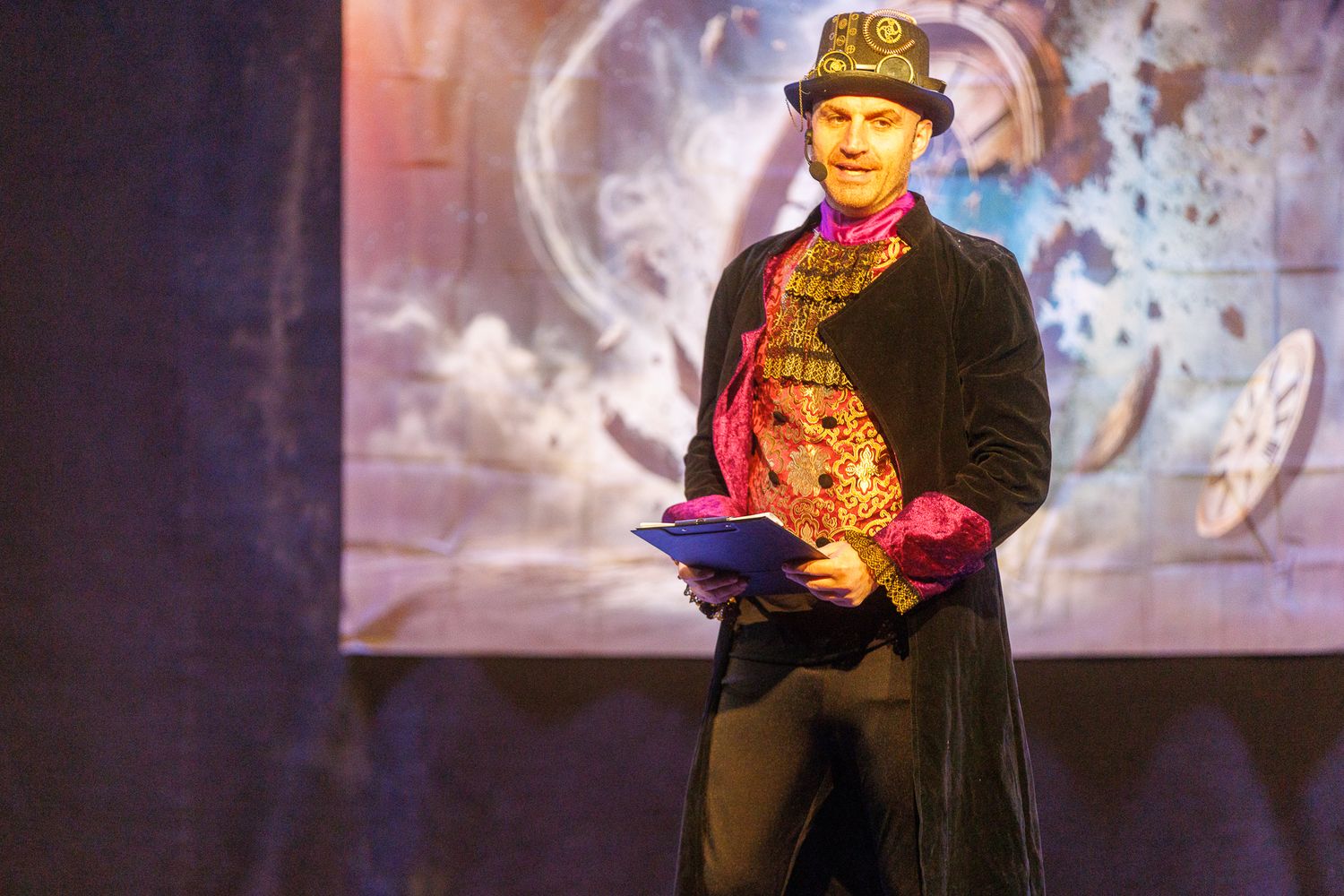 Performers on stage during a theatrical production with projected backdrop.
