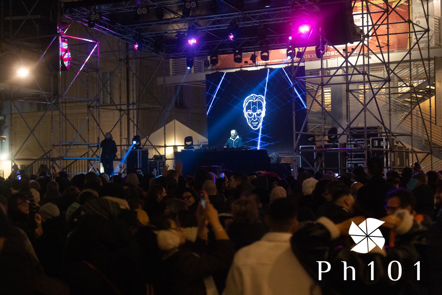 Concert crowd silhouetted against purple and blue stage lighting effects.