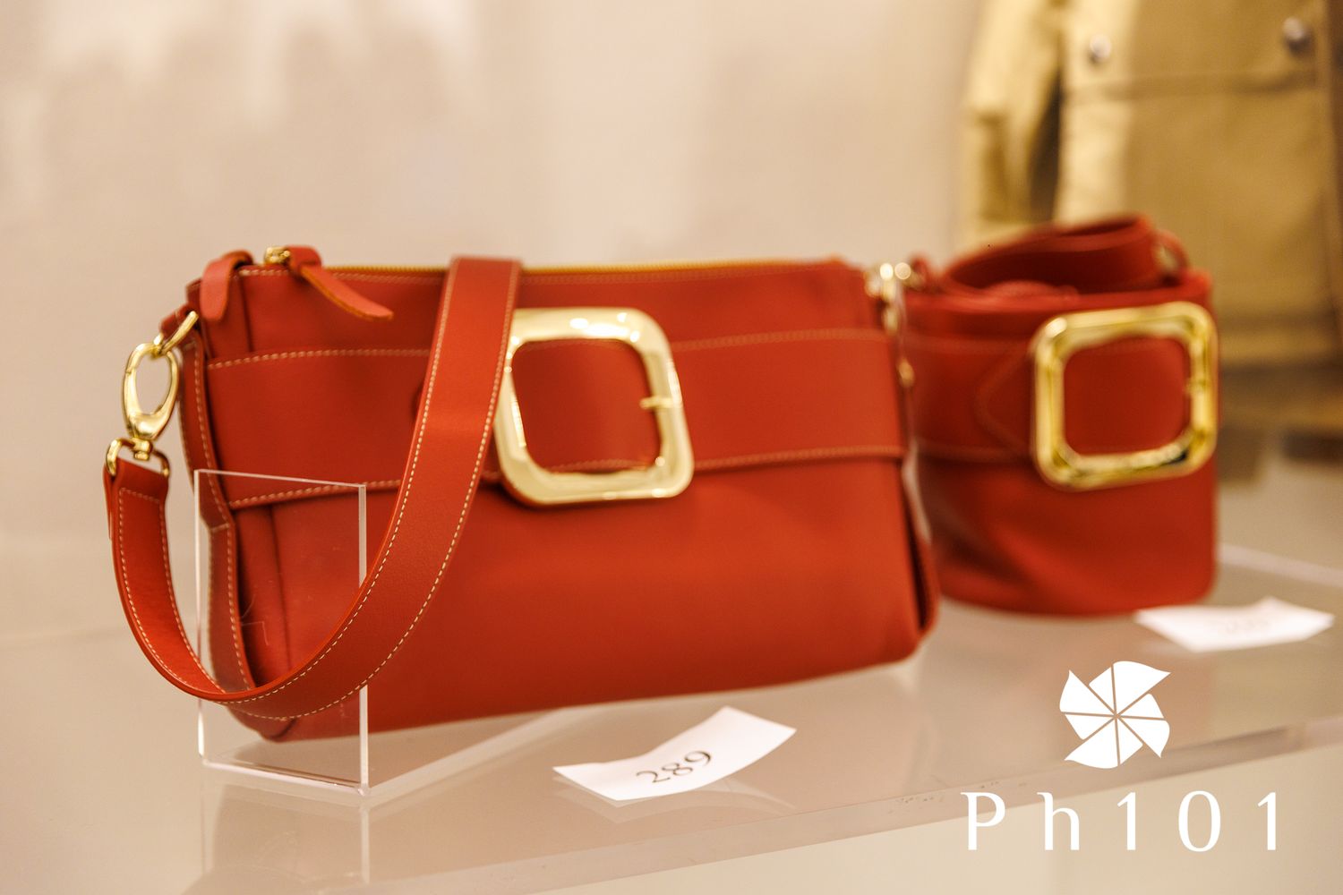 Collection of red leather designer handbags displayed on retail shelf with warm lighting.