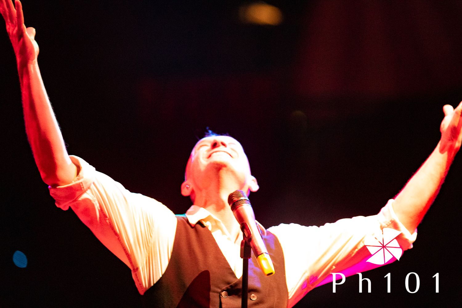 Stage performers illuminated in red lighting during theatrical show.