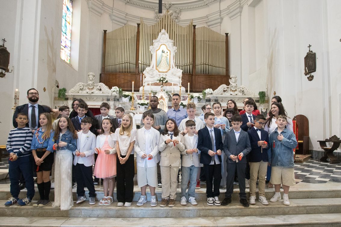 Large group gathered inside ornate white church interior for ceremony.