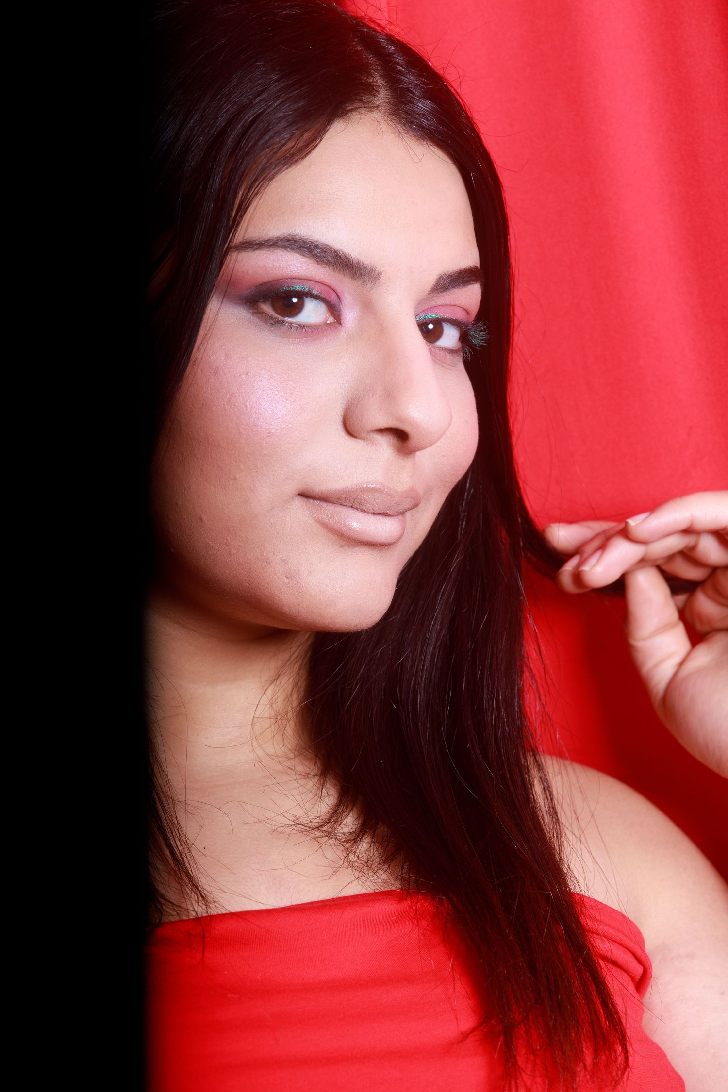 Fashion portrait against a red background featuring soft glamour makeup.