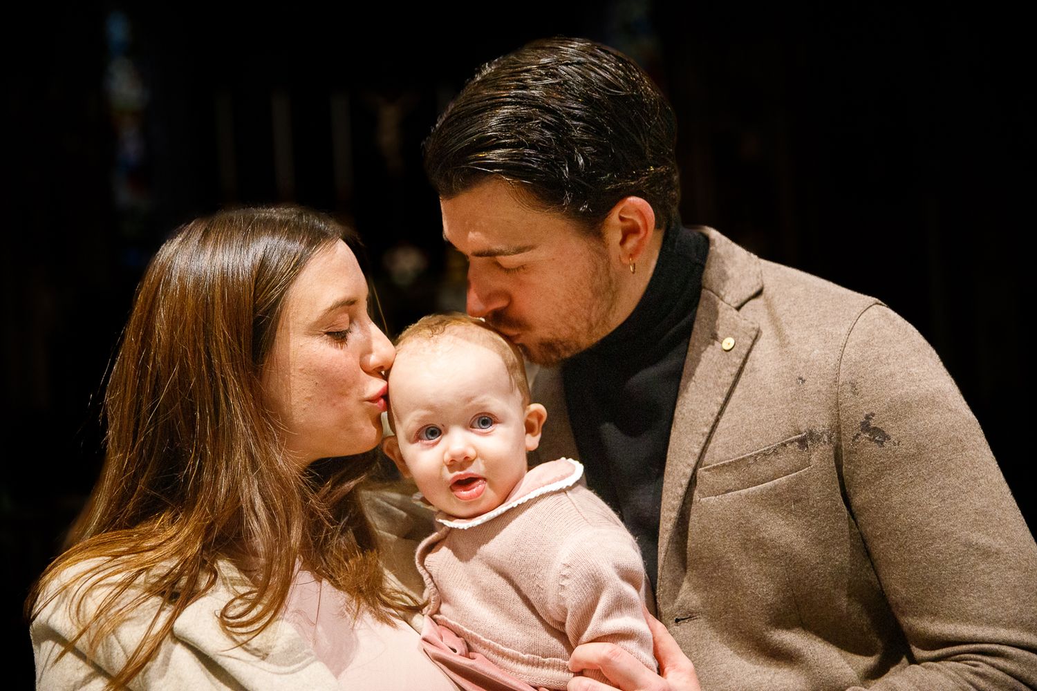 Intimate family moment with baby in warm indoor lighting.