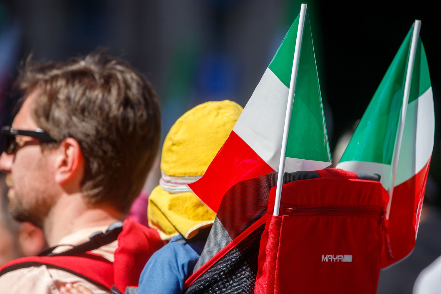 Italian flags wave in a crowd during a ceremonial event.
