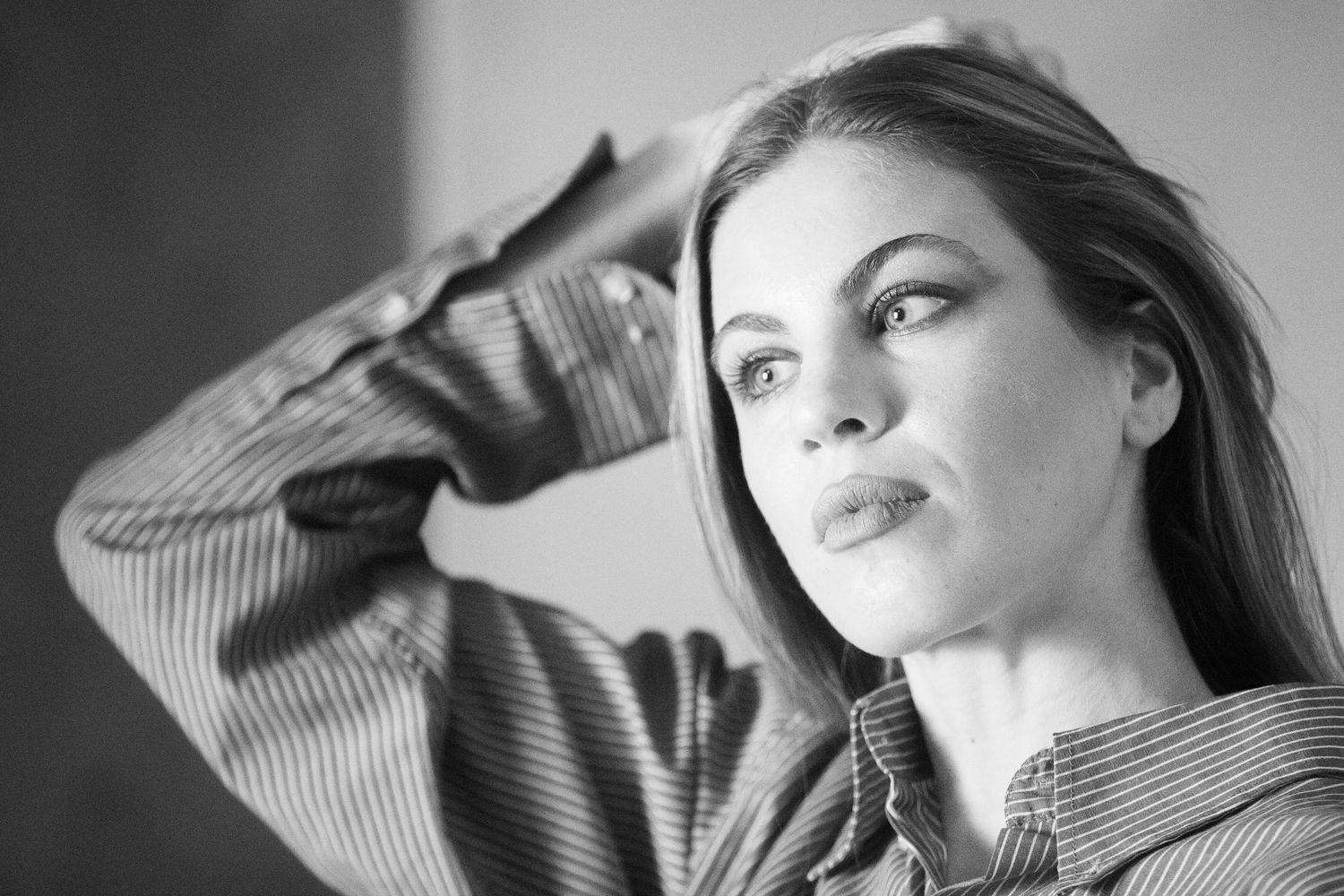 Black and white portrait of a woman in a striped top looking thoughtfully to the side.