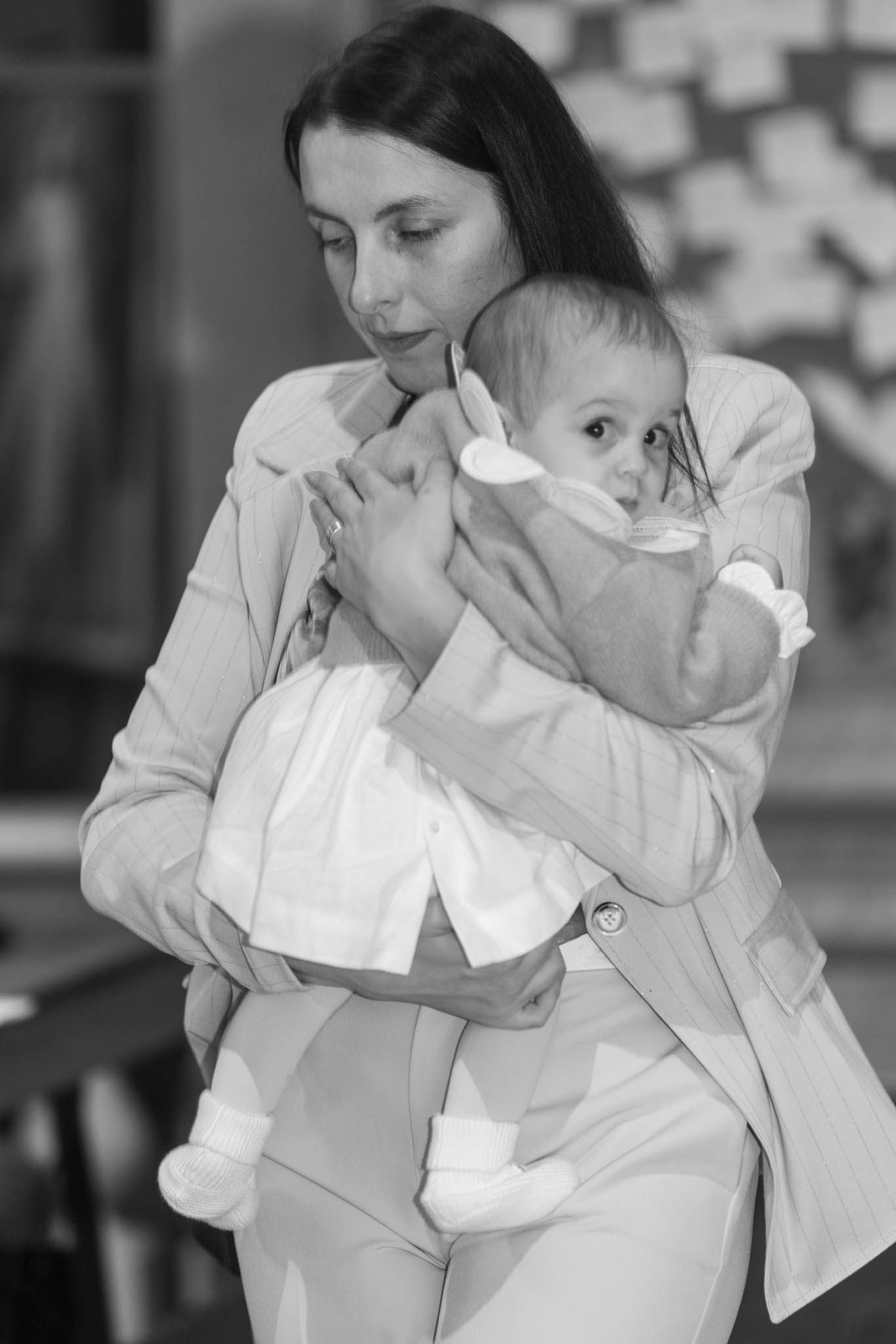 Black and white images showing gentle moments between parent and infant in white clothing.